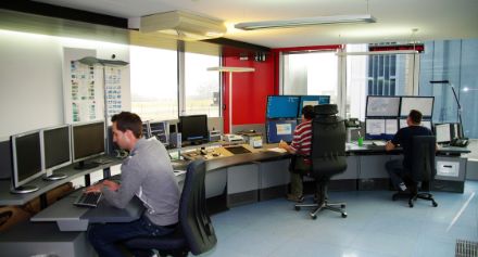 Employees checking several computer screens in the monitoring room.