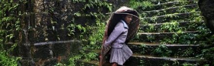 A villager shelters from the rain in a “knups” made from woven bamboo.