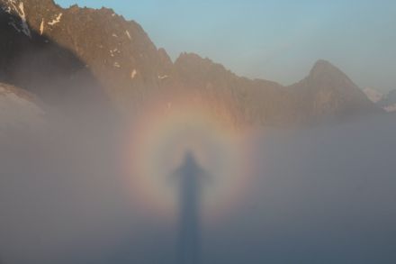 Photograph of a mountain landscape in which coloured rings and the shadow of the observer can be seen on the fog in the foreground.