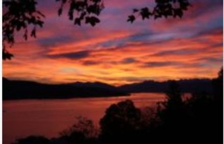 Lake Zurich in the foreground, view towards the east, with reddish-orange sky, partially cloudy.
