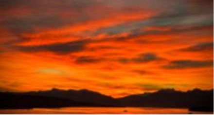 Sunrise over a lake, with mountains in the background.