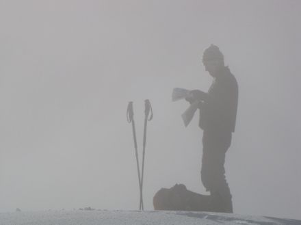 Image of a skier consulting a map in the fog.