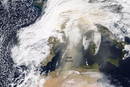 Satellite image of North Africa and Europe. A light yellow dust cloud can be seen over the Mediterranean.