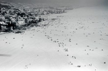 Aerial photograph of the frozen surface of the lake, showing snow and people.