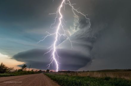  	Image of a rotating storm cloud and a lightning strike over a flat landscape.