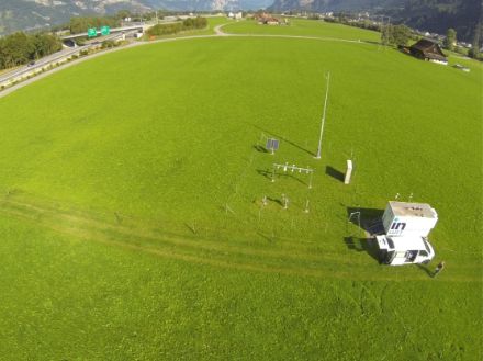 Aerial view of MeteoSwiss, which is located on a meadow. The motorway is visible in the background on the left.